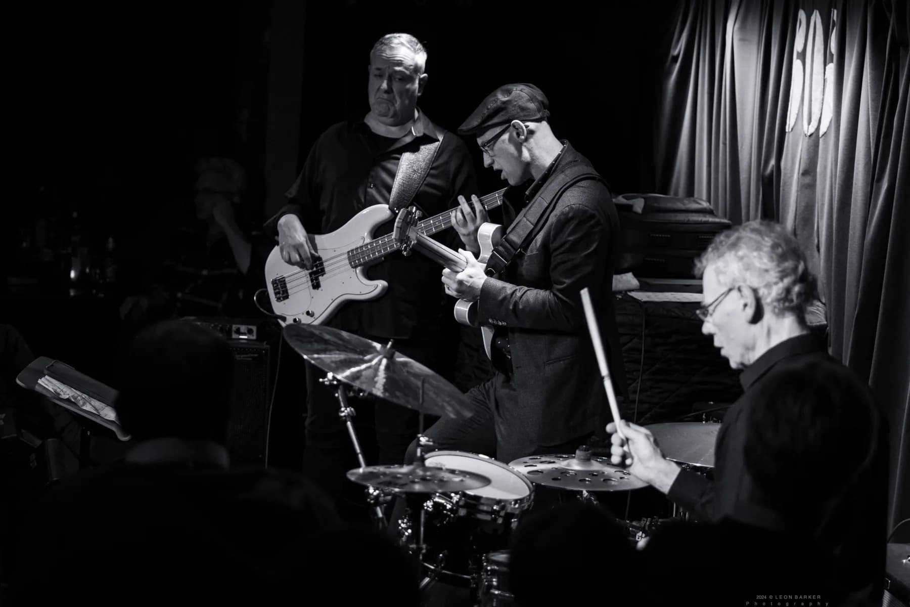 Pete Roth Trio performing in warm red and violet stage light.