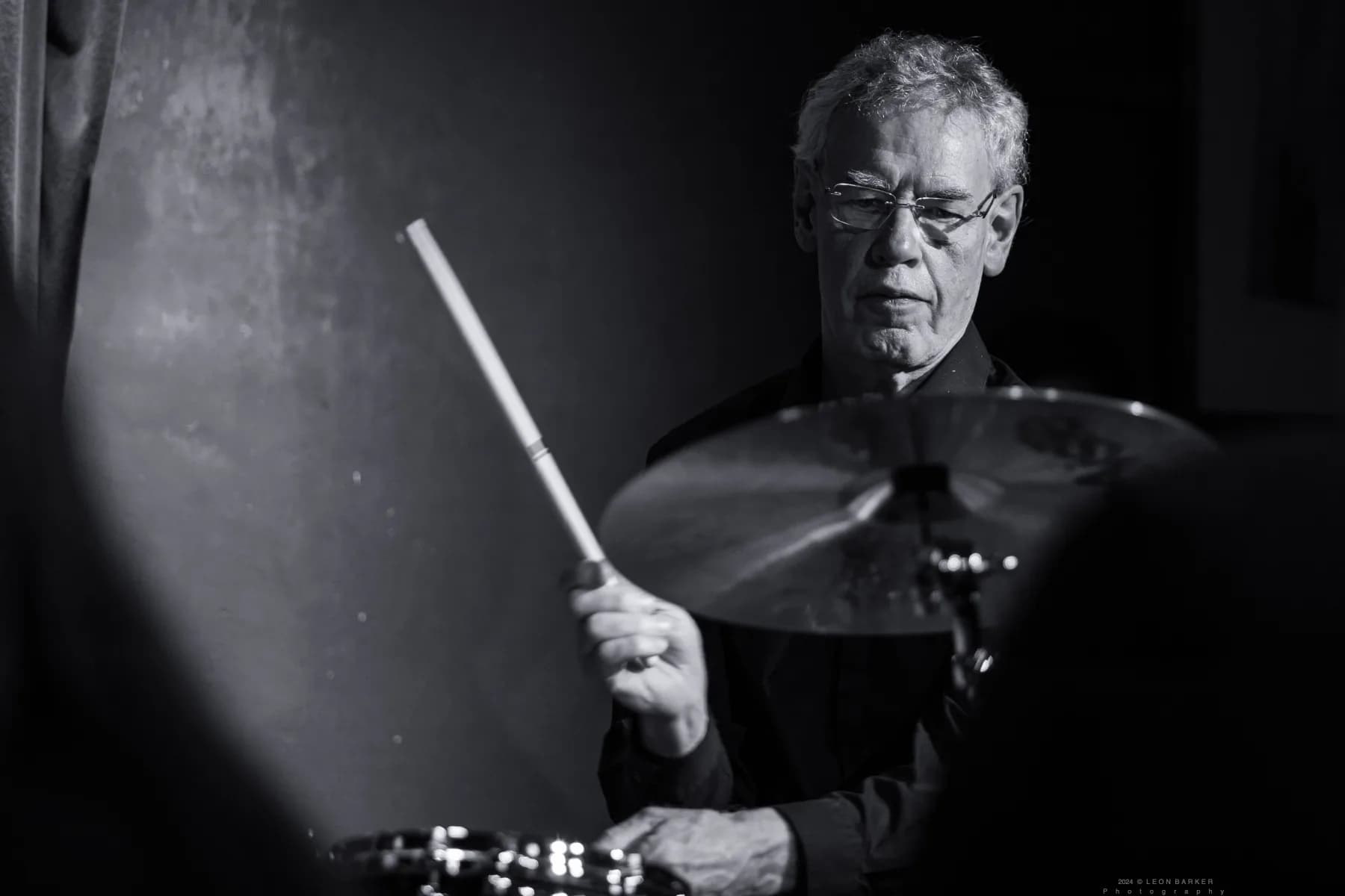 Bill Bruford seated at a drum kit during a Pete Roth Trio performance.