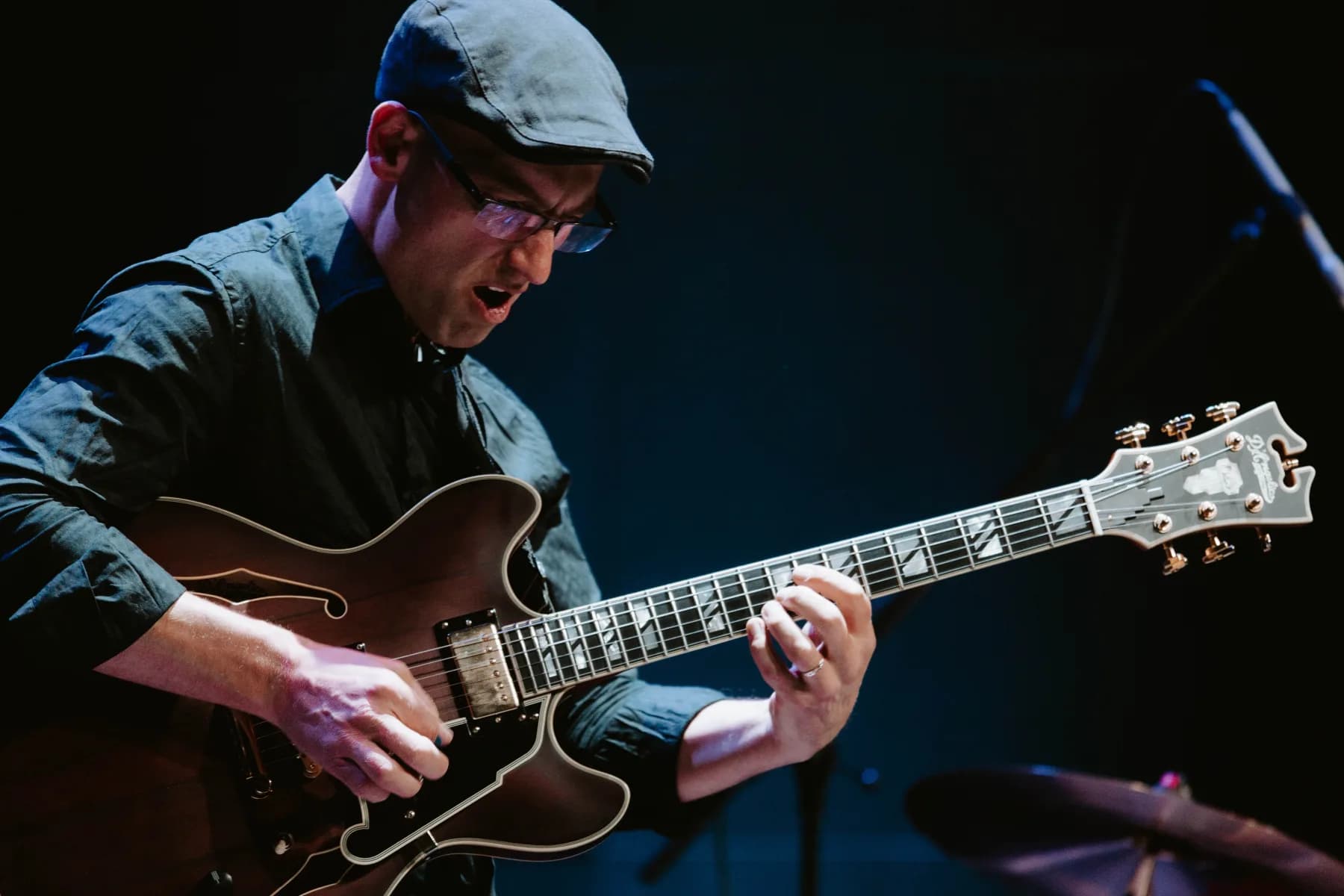 Pete Roth playing electric guitar on a dark stage.